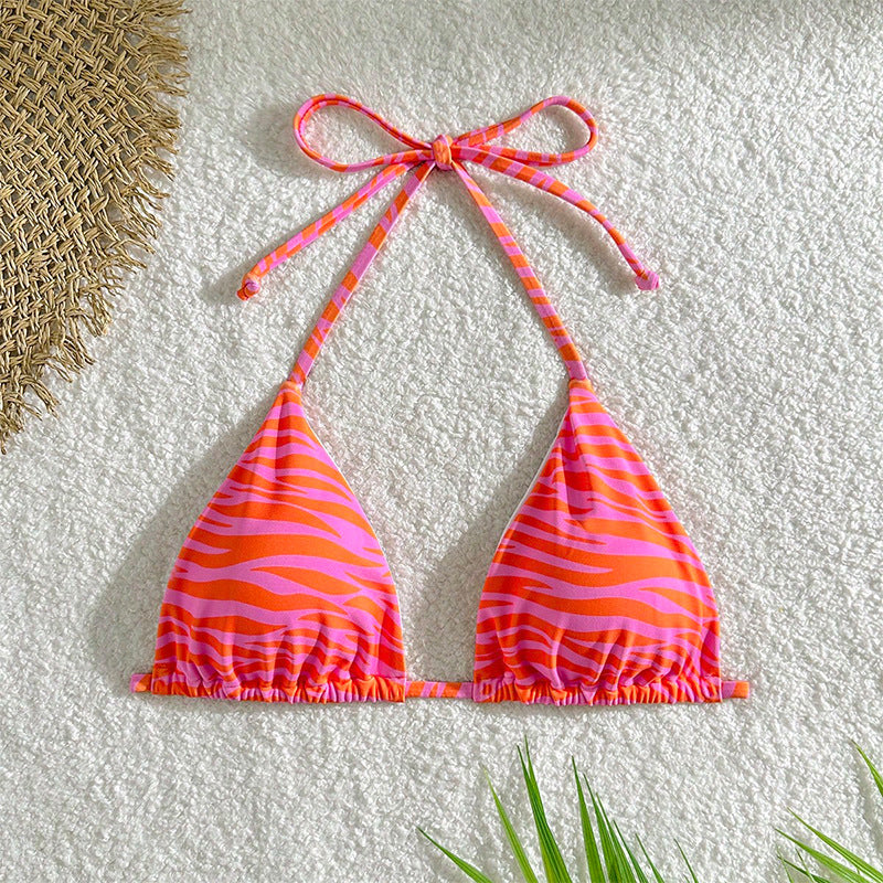 The Zebra Noir Padded Halter Bikini Top in vibrant pink and orange zebra print on a textured background.